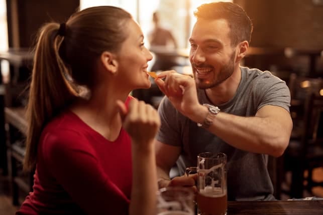 a guy is feeding his girlfriend on a date