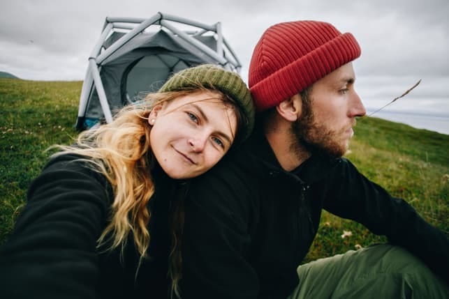 A woman taking a selfie while her man is looking away