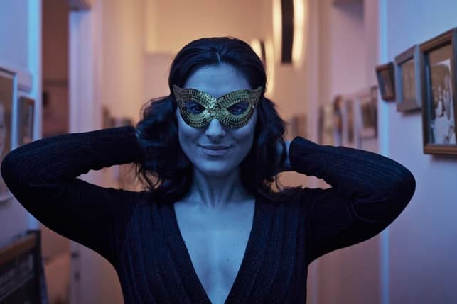 a woman wearing a mask while standing in a dark room