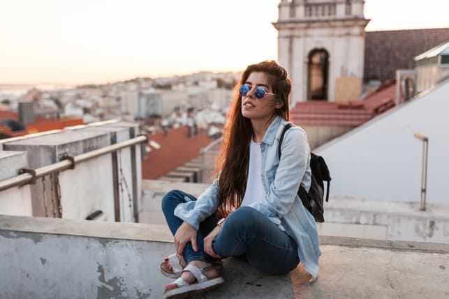 a modern dark-haired woman in sunglasses chilling on a roof