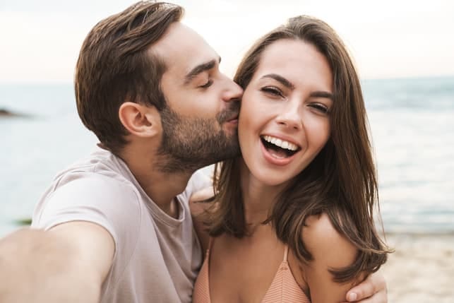 a man is kissing his girlfriend's cheek