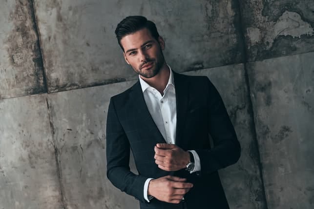 an attractive man in a suit posing outdoors